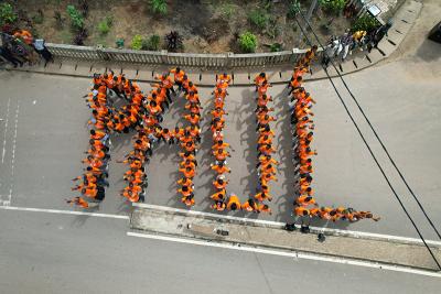 PIH Sierra Leone staff huddle together to spell PAUL from an aerial view.