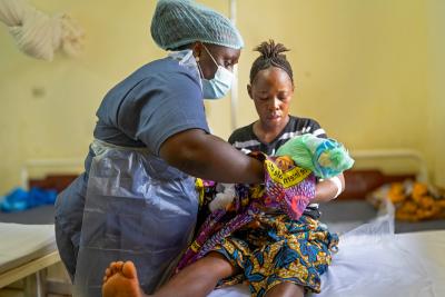 Francess Kamara, midwife mentor, helps Elizabeth Lebbie breastfeed her newborn baby at Koidu Government Hospital. 