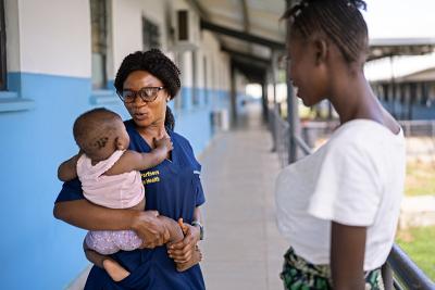 Midwife Aminata B. Kamara, left, holds Bintu, the six-month-old daughter of Fatmata Foday.