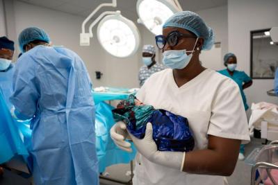 Healthcare worker holding a newborn in an operating room.