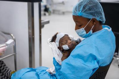 Healthcare worker holding a newborn in an operating room.