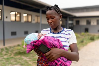 A mother holds her newborn baby standing outside a hospital.