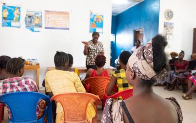 Abi Dauda, wearing head wrap with back to camera, listens to staff in Wellbody’s prenatal care area.