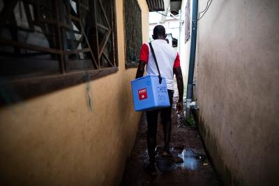 A vaccination team member shoulders a cooler of the temperature-sensitive medicine.