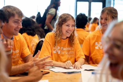 Students wearing orange t-shirts sitting at a table talking