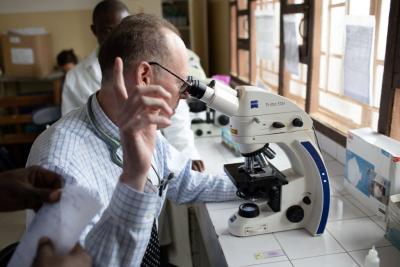 Paul Farmer looking through microscope in Sierra Leone