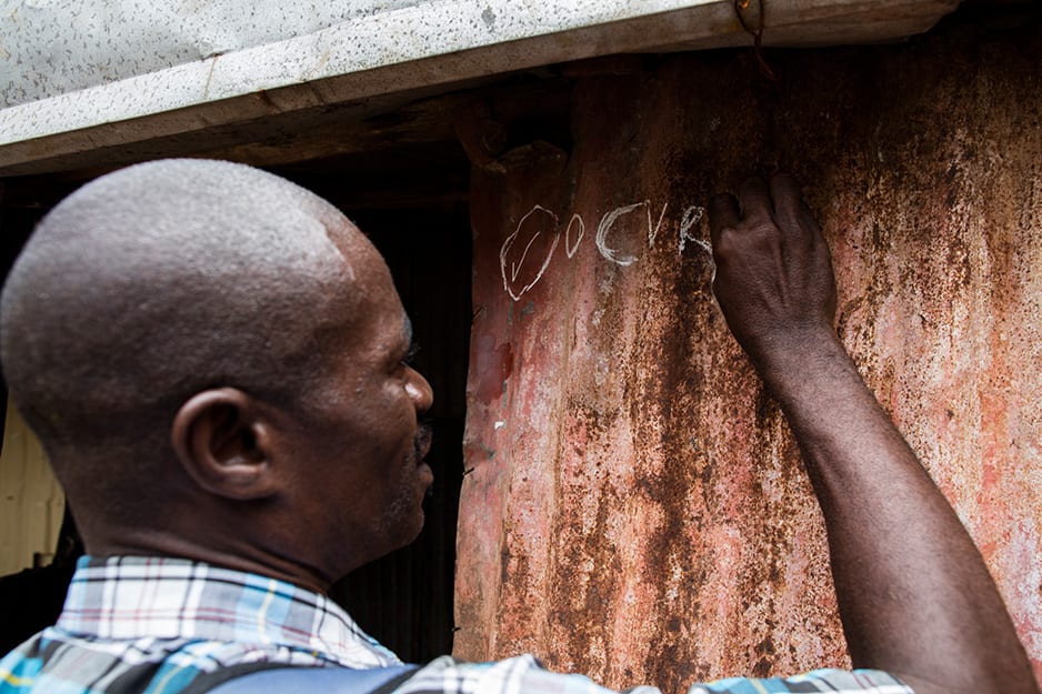 A vaccination team member marks a home in Freetown to show that the family completed the first of two doses.