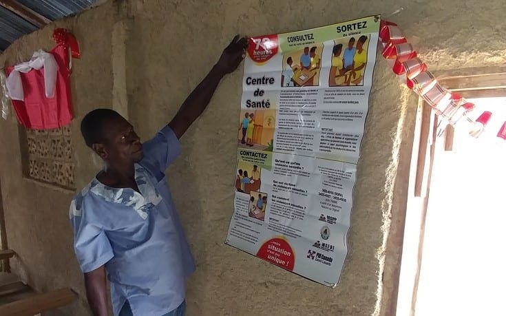 A male GBV Committee member shows a poster on GBV