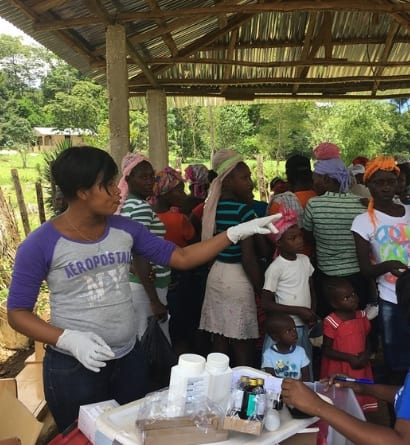 Pharmacy at a mobile nutrition clinic, a staff member stands pointing in front of a group of patients
