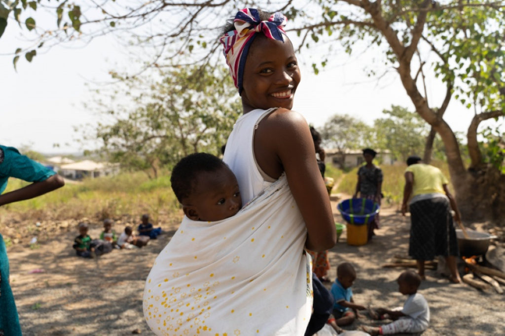 A mother stands with her child on her back at a MAM event in Sierra Leone