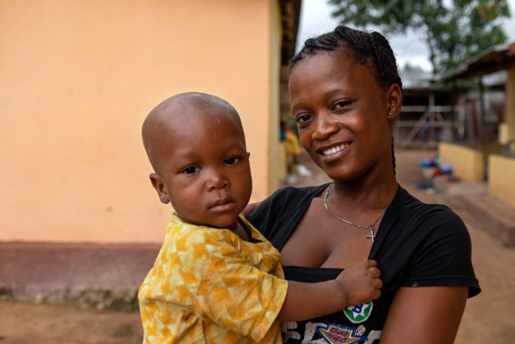 A mother holds her child near Wellbody clinic in Sierra Leone