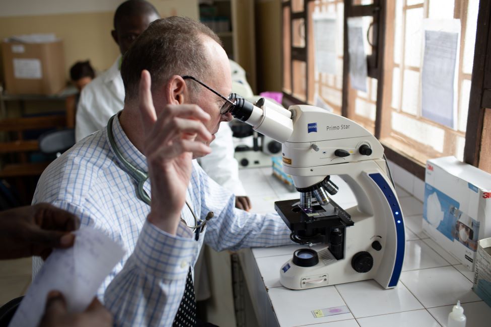 Dr. Paul Farmer looks into a microscope in the KGH lab