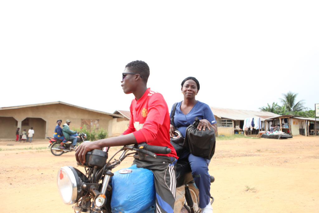 PIH Liberia midwife Habibatu Alu on the back of a motorcycle 