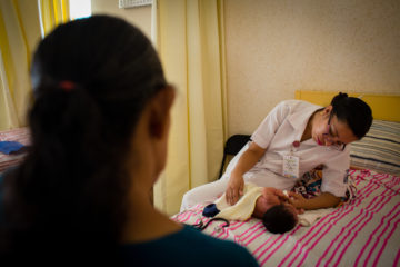 An obstetrics nurse checks in on a newborn.