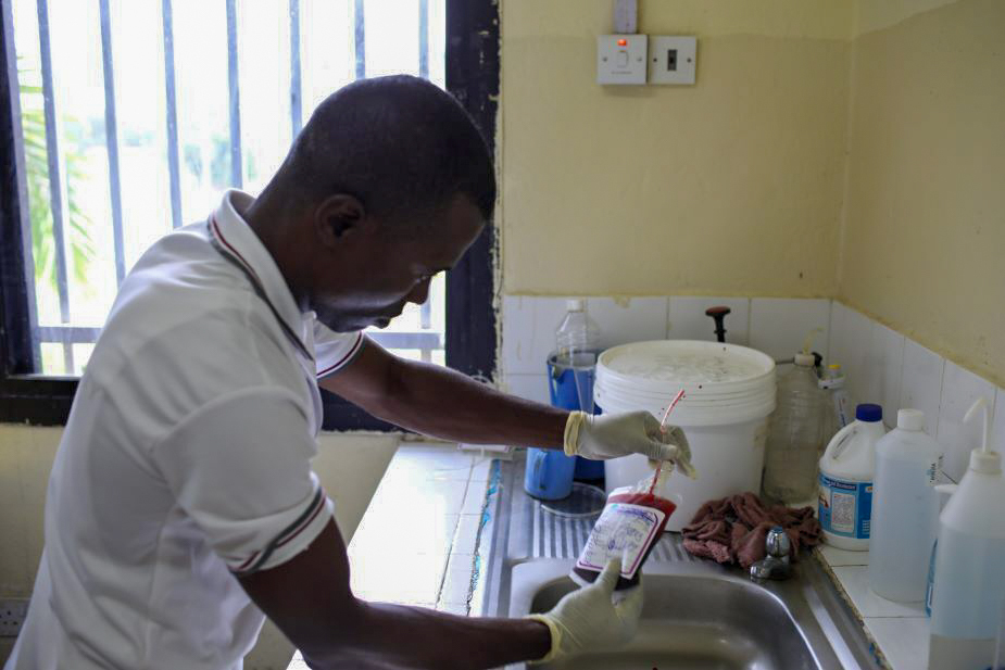 Momodu Mansaray, a lab tech at the blood bank, handles a bag of blood.