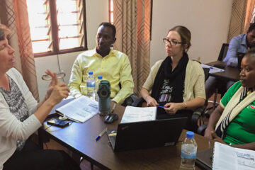 Dr. Ann Miller of Harvard Medical School (HMS), at left and senior mentor in a research training program hosted in Rwanda by HMS and Partners In Health, talks with (left to right) trainee Alain Ahishaliye of PIH; Katie Beck, then senior nutrition program manager for PIH in Rwanda; and trainee Marie Clarie Abimana, a registered nurse midwife and quality improvement advisor for PIH.