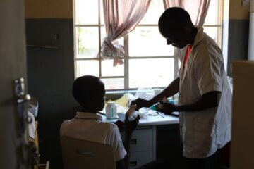 NCD nurse Victor Kaphaso advises teen diabetes patient Kerefasi Wiliyamu about his insulin, in the pharmacy room of PIH's Advanced NCD Clinic at Lisungwi Community Hospital in Neno District, Malawi.